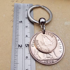 Pu&ograve; includere: Un portachiavi vintage con due monete di rame. La moneta pi&ugrave; grande &egrave; un penny del 1946 e la pi&ugrave; piccola &egrave; un farthing. Il portachiavi ha un anello in metallo color argento. Le monete hanno un diametro di circa 3,2 cm.