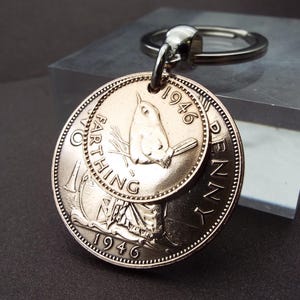 Puede incluir: Un llavero con monedas antiguas, incluyendo un Farthing y un Penny de 1946. El Farthing presenta un p&aacute;jaro, y el Penny un retrato de mujer. El llavero es de metal con un anillo plateado.