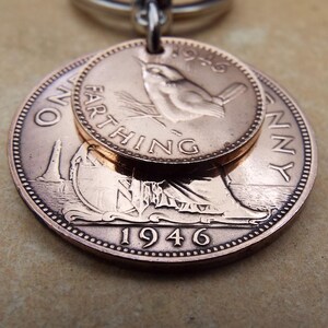 Pu&ograve; includere: Un ciondolo color rame con due monete britanniche vintage. La moneta pi&ugrave; grande mostra l'anno 1946 e una figura seduta, mentre quella pi&ugrave; piccola mostra un uccello e la parola "FARTHING". Il ciondolo &egrave; attaccato a un anello color argento.