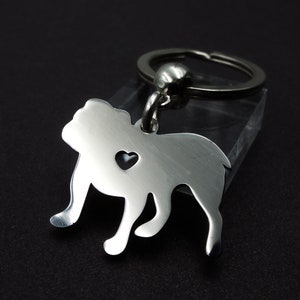 May include: Silver bulldog keychain with a heart cutout. The keychain is attached to a silver key ring.
