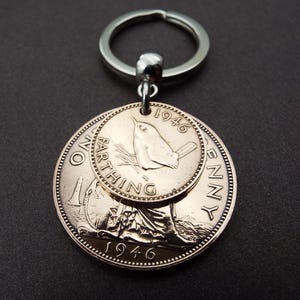 Puede incluir: Un llavero plateado con dos monedas antiguas. La moneda m&aacute;s grande es un penique, y la m&aacute;s peque&ntilde;a es un farthing, ambas de 1946. El farthing tiene un dise&ntilde;o de p&aacute;jaro. El llavero est&aacute; sujeto a un anillo plateado.