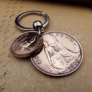 Puede incluir: Un llavero con dos monedas de color cobre. Una moneda es ovalada con un dise&ntilde;o de p&aacute;jaro y el a&ntilde;o 1946. La otra moneda es redonda con una figura sentada, la palabra "PENNY" y el a&ntilde;o 1946. El llavero tiene un anillo plateado.