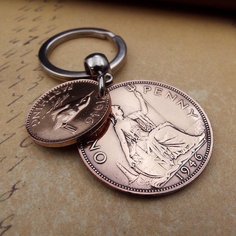 Puede incluir: Un llavero con dos monedas de color cobre. Una moneda es ovalada con un dise&ntilde;o de p&aacute;jaro y el a&ntilde;o 1946. La otra moneda es redonda con una figura sentada, la palabra "PENNY" y el a&ntilde;o 1946. El llavero tiene un anillo plateado.
