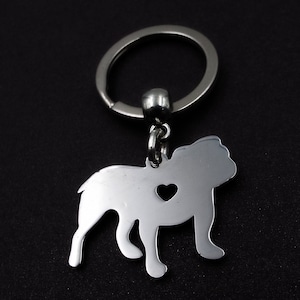 May include: Silver bulldog keychain with a heart cut out of the body. The keychain is attached to a silver key ring.
