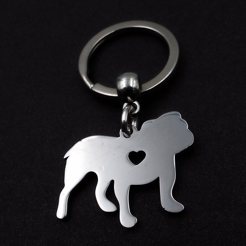 May include: Silver bulldog keychain with a heart cut out of the body. The keychain is attached to a silver key ring.