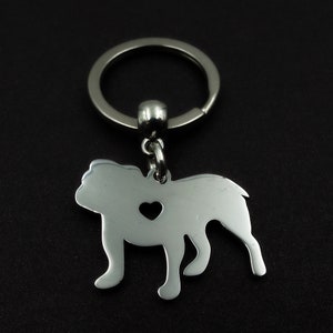 May include: Silver bulldog keychain with a heart cut out. The keychain is attached to a silver key ring.