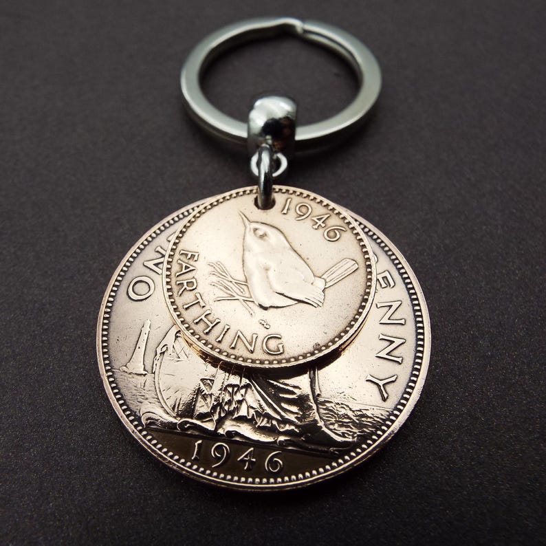 Pu&ograve; includere: Un portachiavi argentato con due monete d'epoca. La moneta pi&ugrave; grande &egrave; un penny, e la pi&ugrave; piccola &egrave; un farthing, entrambe del 1946. Il farthing ha un disegno di uccello. Il portachiavi &egrave; attaccato a un anello d'argento.