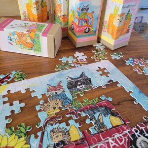 May include: A 120-piece jigsaw puzzle featuring a red truck with a variety of animals riding inside. The truck has the words "I need a road trip" written on the side. The puzzle is on a wooden table with some of the pieces already assembled.
