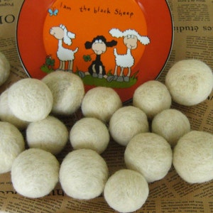 May include: A close-up of a group of white wool dryer balls. The balls are arranged in a circle on a brown and white patterned surface. The balls are soft and fluffy, and they are perfect for adding a natural touch to your laundry routine.