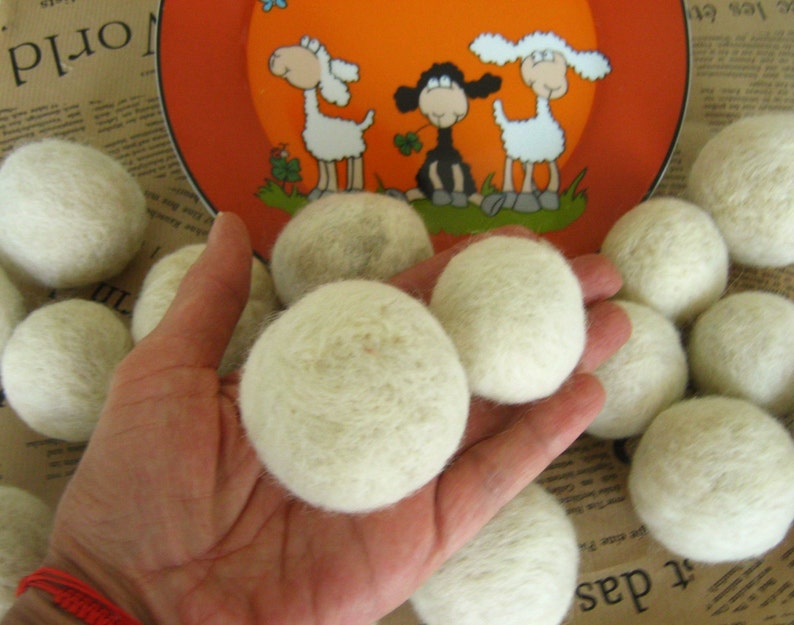 May include: A hand holding a pile of white wool dryer balls. The balls are soft and fluffy, and they are perfect for adding a natural touch to your laundry routine.