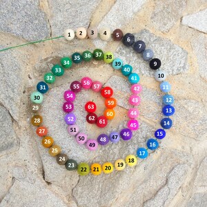 Pode incluir: Uma roda de cores de 63 bolas de feltro, dispostas em espiral. As bolas s&atilde;o numeradas de 1 a 63, e cada bola &eacute; de uma cor diferente.