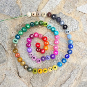 May include: A color wheel of 63 felt balls, arranged in a spiral pattern. The balls are numbered 1 through 63, and each ball is a different color.