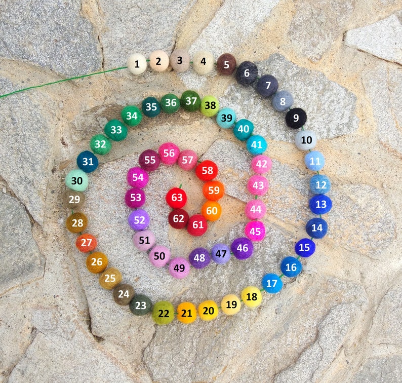 May include: A color wheel of 63 felt balls, arranged in a spiral pattern. The balls are numbered 1 through 63, and each ball is a different color.