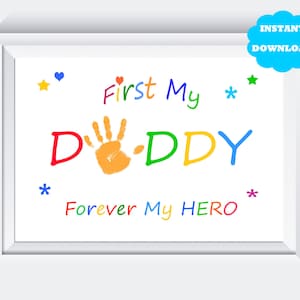 Puede incluir: Una impresión de arte imprimible con una huella de mano y el texto "First My DADDY Forever My HERO" en colores arcoíris. La impresión está enmarcada en un marco blanco.