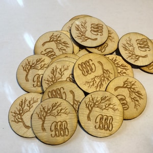 May include: A pile of round, wooden coasters with a laser-etched design of a tree branch and the letters "BBB".