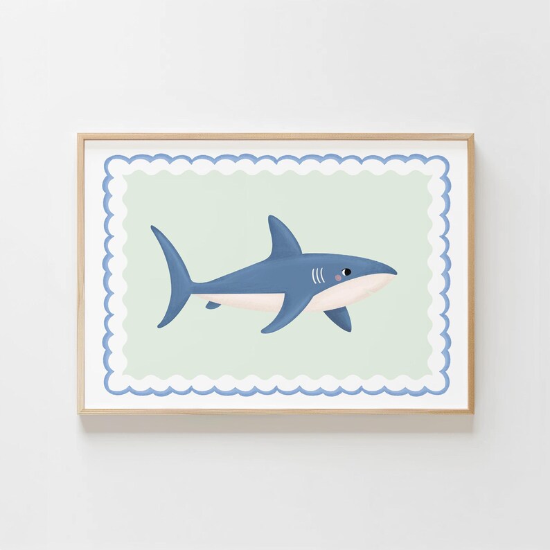 May include: A framed print featuring a blue shark illustration. The shark is depicted in a side profile with a white belly and a light blue body. The background is a light green colour with a scalloped border.