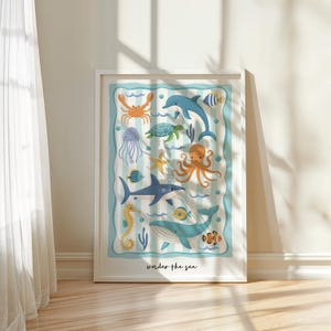 May include: A framed art print featuring colorful illustrations of sea creatures, including a crab, dolphin, shark, and octopus. The artwork has a striped background with the words "under the sea" at the bottom.
