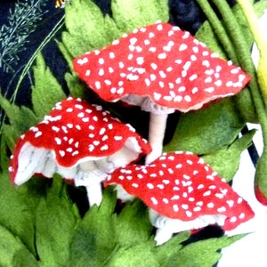 May include: A black felt bag with a green felt handle and three red and white felt mushrooms attached to the front.