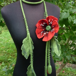 May include: A green felt necklace with a red felt poppy flower and green felt leaves. The necklace is on a black mannequin.