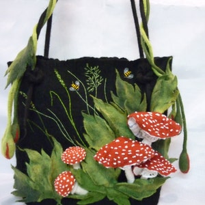 May include: A black felt tote bag with a drawstring closure. The bag is decorated with green felt leaves, red and white felt mushrooms, and embroidered bees and grass.