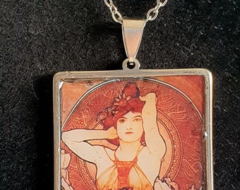 Colgante romántico al estilo del gran artista A. Mucha, con montura y cadena plateadas que no se deslustran. Estilo boho chic, una joya encantadora que evoca nostalgia.