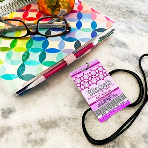 May include: Purple and silver Bat Mitzvah invitation with a ticket design. The invitation reads "Elizabeth is called to the Torah as a Bat Mitzvah".
