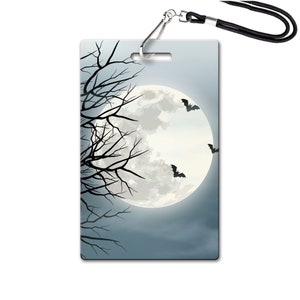 May include: A Halloween-themed lanyard with a full moon and bats against a dark blue sky. The lanyard is made of black fabric and has a silver clip.