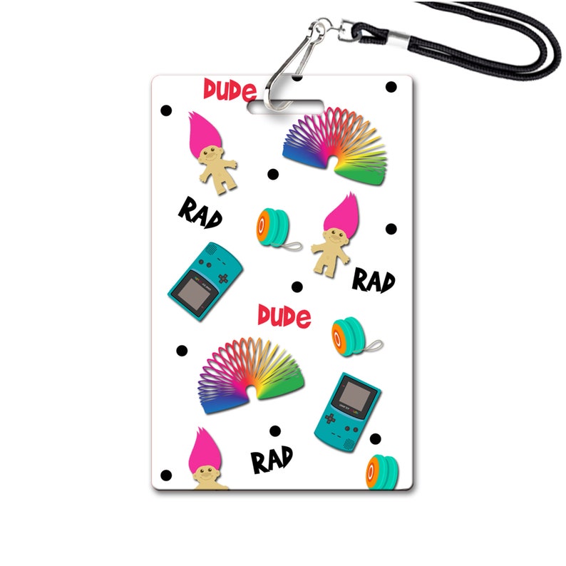 May include: White plastic badge with a lanyard. The badge has a repeating pattern of a troll doll, a slinky, a yo-yo, a Game Boy, and the words "Dude", "Rad", and "Rad".