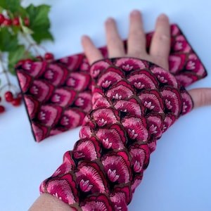 May include: A pair of pink and black fingerless gloves with a floral pattern. The gloves are made of a soft, stretchy fabric and are perfect for keeping your hands warm in the cooler months.