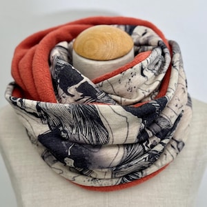 May include: A reversible infinity scarf with a black and white floral print on one side and a solid coral colour on the other side.