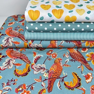 Può includere: Un mucchio di cinque campioni di tessuto con diversi motivi. Il campione superiore è bianco con cuori gialli e punti verdi. Il secondo campione è verde acqua con pois bianchi. Il terzo campione è verde acqua con strisce bianche. Il quarto campione è verde acqua con un motivo floreale con uccelli arancioni. Il campione inferiore è verde acqua con un motivo floreale con uccelli arancioni.