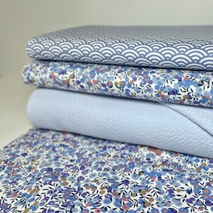 Könnte beinhalten: Ein Stapel von vier Stoffproben in Blautönen. Die oberste Probe zeigt ein weiß-blaues geometrisches Muster, die zweite und vierte Probe zeigen einen weißen Hintergrund mit einem kleinen blauen Blumenmuster und die dritte Probe ist einfarbig hellblau.