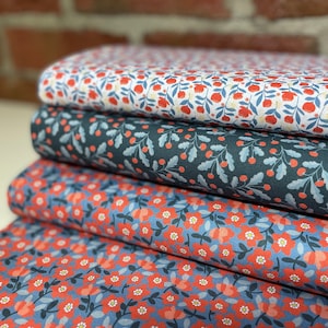 Op de afbeelding: Vier stofstalen met bloemenpatronen. De bovenste staal is wit met rode bloemen, de tweede is donkerblauw met rode bessen, de derde is blauw met rode bloemen en de onderste is blauw met rode bloemen.