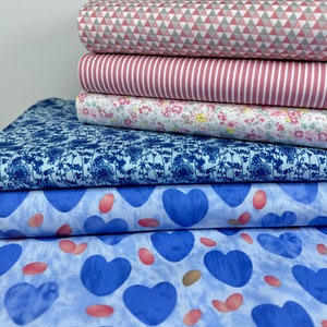 May include: Stack of five different patterned fabric swatches. The top swatch is a pink and grey geometric pattern, the second is a pink and white striped pattern, the third is a white floral pattern, the fourth is a light blue fabric with a dark blue floral pattern, and the bottom swatch is a light blue fabric with a blue heart pattern and pink dots.
