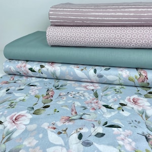 May include: Four different fabric swatches stacked on top of each other. The top swatch is a light pink with white stripes. The second swatch is a light pink with a white circle pattern. The third swatch is a light teal. The bottom swatch is a light blue with a watercolour floral pattern featuring pink flowers and hummingbirds.