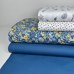 Könnte beinhalten: Ein Stapel aus vier Stoffproben. Die unterste Probe ist einfarbig dunkelblau. Die zweite Probe ist hellblau mit einem kleinen gelben Blumenmuster. Die dritte Probe ist weiß mit schwarzen Punkten. Die oberste Probe ist weiß mit einem schwarzen Blumenmuster.