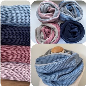 Könnte beinhalten: Vier verschiedene Farbkombinationen eines doppelseitigen Strick-Infinity-Schals. Der Schal ist aus einem weichen, strukturierten Strickstoff gefertigt. Der Schal ist in Blau, Rosa, Grau und Marineblau zu sehen.