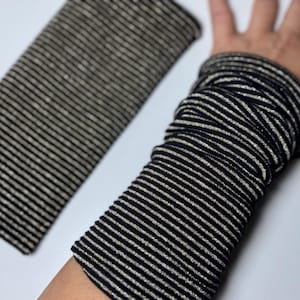 Puede incluir: Calentadores de brazo de tela a rayas negras y plateadas. La tela es el&aacute;stica y tiene un brillo sutil.