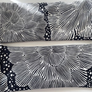 May include: Two black and white eye pillows with a geometric pattern. The pattern is made up of lines and dots.
