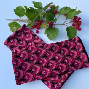 May include: A pair of pink and black fingerless gloves with a floral pattern. The gloves are made of a soft, stretchy fabric and have a black trim.