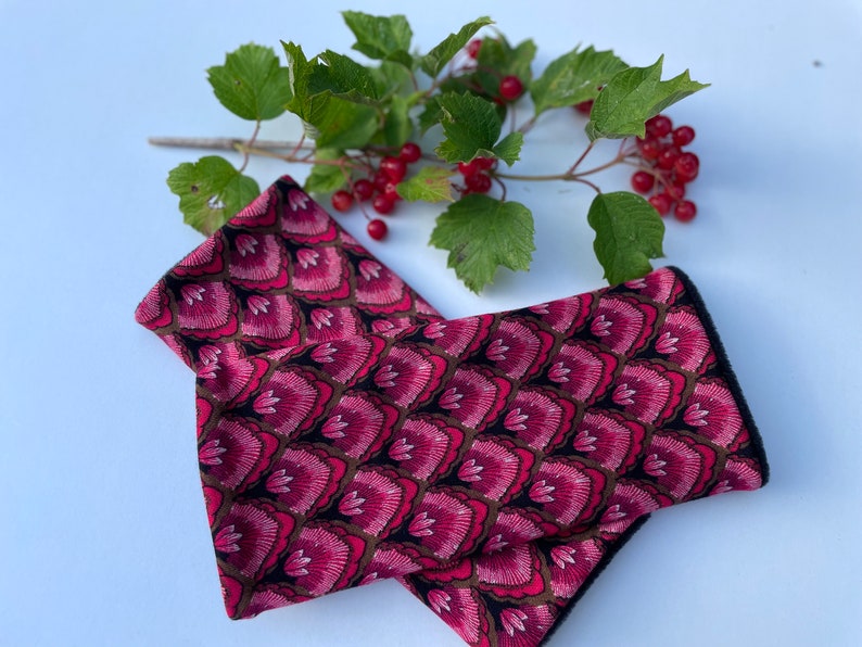 May include: A pair of pink and black fingerless gloves with a floral pattern. The gloves are made of a soft, stretchy fabric and have a black trim.