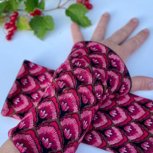 May include: A pair of pink and black arm warmers with a floral pattern. The arm warmers are made of a soft, stretchy fabric and are perfect for keeping your arms warm in the cooler months.