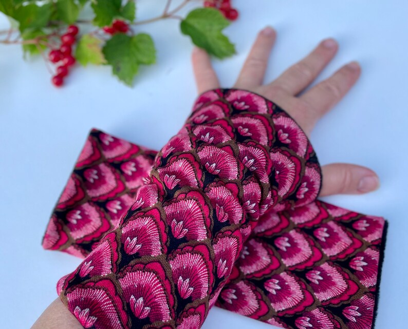 May include: A pair of pink and black arm warmers with a floral pattern. The arm warmers are made of a soft, stretchy fabric and are perfect for keeping your arms warm in the cooler months.