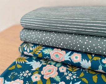 Op de afbeelding: Een stapel van vier stofstalen in verschillende patronen. De bovenste staal is lichtgrijs met witte strepen, de tweede is lichtgrijs met witte stippen, de derde is donkerblauw met een bloemenpatroon en de onderste staal is donkerblauw met een bloemenpatroon.
