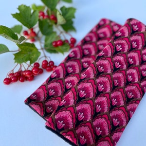 May include: Two pink and black patterned fabric seatbelt covers. The fabric has a repeating pattern of pink flowers with brown accents on a black background.