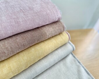 Può includere: Un mucchio di cinque campioni di tessuto in varie tonalità di beige, marrone e viola. I campioni sono realizzati in un materiale simile al lino con una texture sottile.