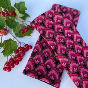 May include: A pair of pink and brown fabric wrist warmers with a floral pattern. The warmers are made of a soft, comfortable material and are perfect for keeping your hands warm in the cold weather.