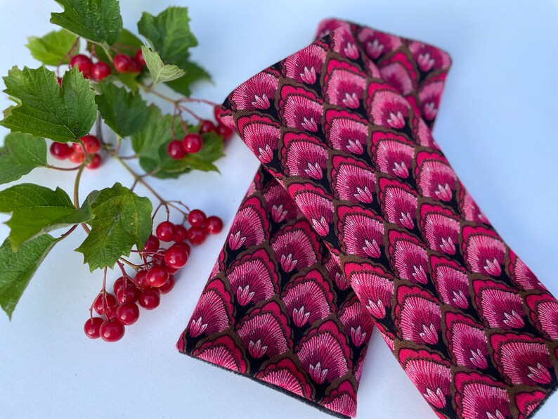 May include: A pair of pink and brown fabric wrist warmers with a floral pattern. The warmers are made of a soft, comfortable material and are perfect for keeping your hands warm in the cold weather.