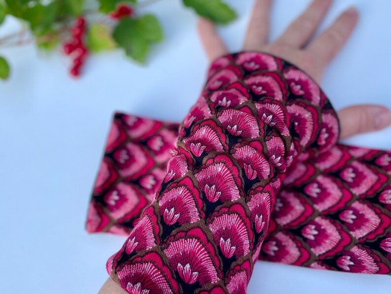 May include: A pair of pink and brown arm warmers with a floral pattern. The warmers are made of a soft, stretchy fabric and are perfect for keeping your arms warm in the cooler months.