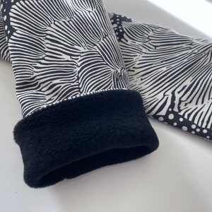 May include: Black and white patterned fingerless gloves with a black fleece lining.